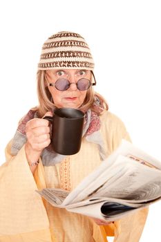 Crazy new age woman in a yellow robe with coffee cup and newspaper