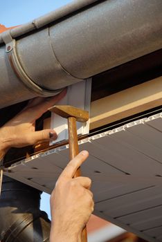 working hand with hammer and nail under house roof outdoor