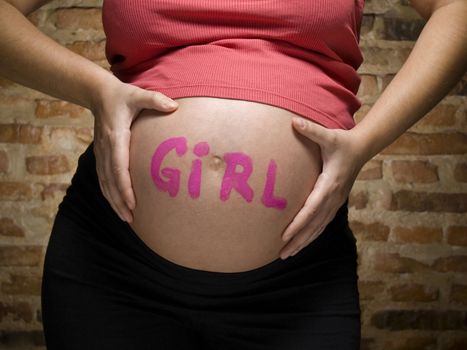 Pregnant woman with the word GIRL written in her belly.