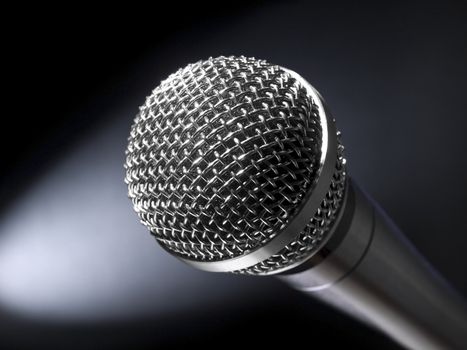 A dynamic microphone on stage. Bright spot light on the background.