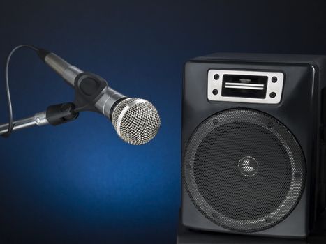 Professional microphone and speaker over a diffuse blue background.