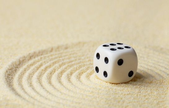 Dice with black dots against yellow sand