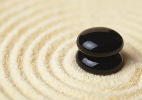 Two black stones put in a pile against sand