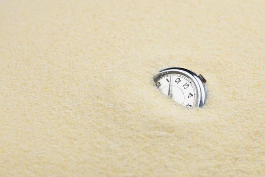 Ancient mechanical watch sinks in sand symbolize leaving time