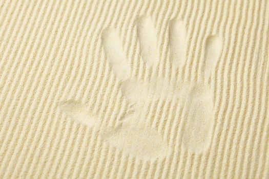 Trace from a palm on a surface of yellow sand