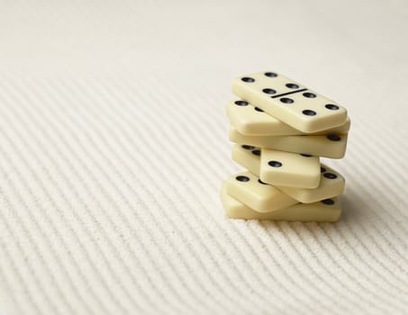 Dominoes pile on a surface of sand - an abstract composition