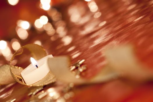 Festive background - burning tealight with ribbon. Selective focus on flame. aRGB.