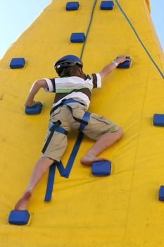 A young agile child climbs a wall.  Some slight movement.