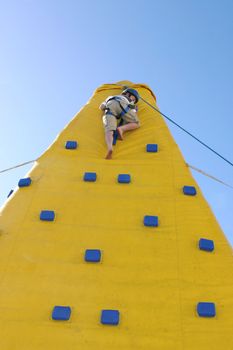 A boy makes the jouney down from the top of a climbing wall.