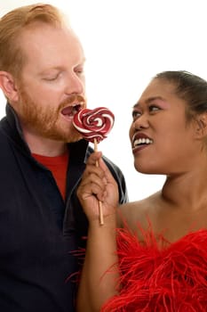Happy couple sharing a red and white lollipop