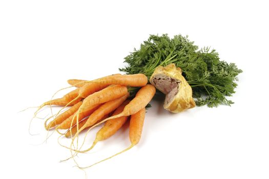 Contradiction between healthy food and junk food using bunch of carrots and pork pie on a reflective white background 