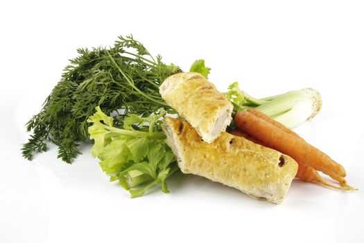 Contradiction between healthy food and junk food using a bunch of carrots and celery with a sausage roll on a reflective white background 