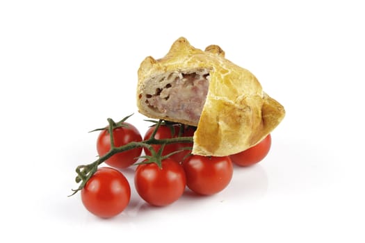 Contradiction between healthy food and junk food using tomatoes and a pork pie on a reflective white background 