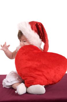 Baby with a little red heart and a christmas hat