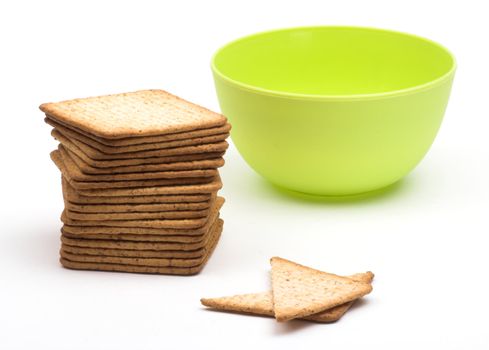 A stack of crackers  and green cup over white
