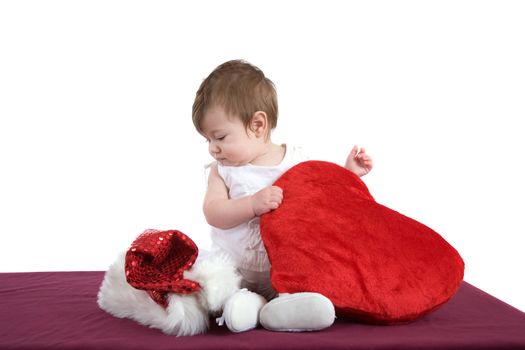 Cute baby girl looking a bit surprised at the santa hat lying next to her