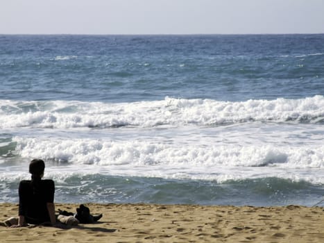 Young relaxed woman watching glistening waves of the ocean