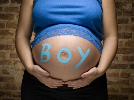 Pregnant woman with the word BOY written in her belly.