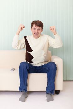 The person on a sofa watches football on TV