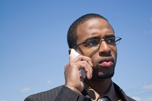 A young African American man talking on his cellular phone with a concerned or serious look on his face.