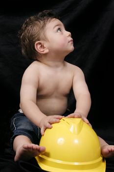 Young toddler plays with a bright yellow hardhat.