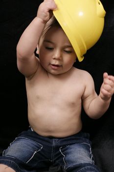 A child plays with a builder's construction hat.