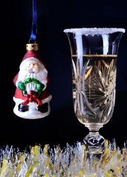 One glass of champagne on black bokeh background with little Santa