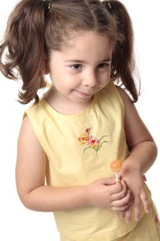 A toddler girl dressed in a yellow outfit smiles shyly