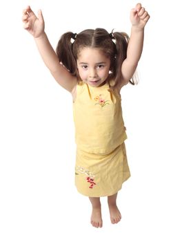 Little toddler girl with both arms raised above her head.  She is smiling and has hair in ponytails, 