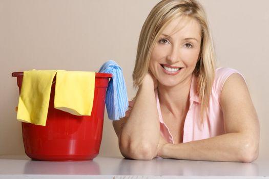 This image depicts a woman with a cleaning bucket, gloves and cleaning cloth.  
