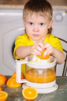 The child in a yellow vest to wring out juice  from an orange