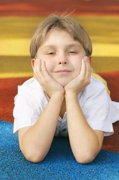 Boy on colorful playground matting with a happy disposition / outlook.