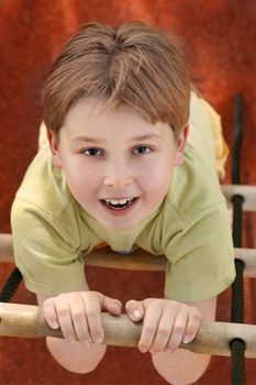 Young boy climbs a rope ladder.
Above perspective.