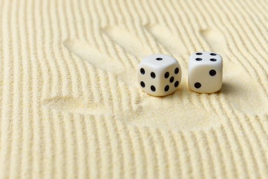 Dices on a sand surface and a palm print - an abstract art composition in yellow tones