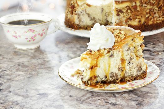 Slice of Southern Pecan Cheesecake with hot coffee in background. Extreme shallow depth of field with selective focus on slice of pie in foreground. Reflection can be seen on granite surface.