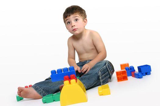 Young boy sits amongst colourful generic building blocks.