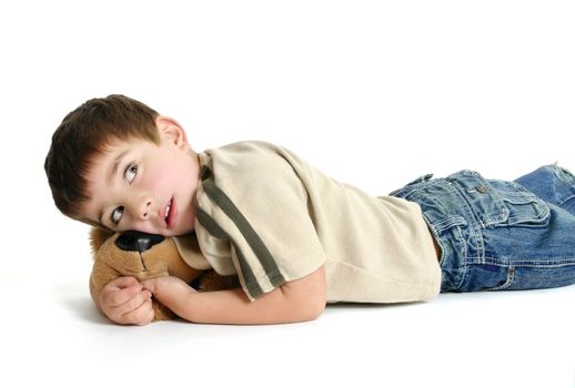 Toddler boy lying on the floor with a toy and thinking.