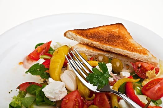 greek salad on a plate with a slice of toast bread