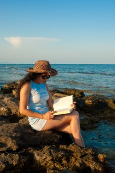 Woman ejoying a book with her feet in the water