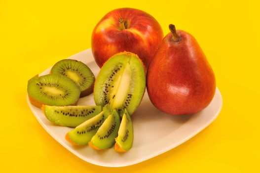 
 sliced kiwi, sliced pear and apple on a white plate 