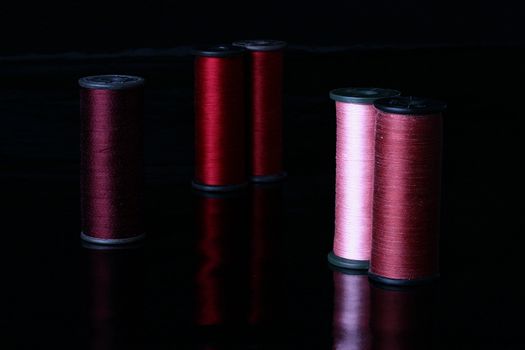 Colour threads on coils, a background - black, reflecting.