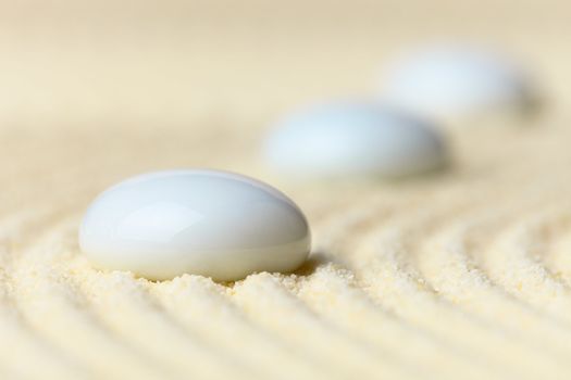 Three white drops on a surface of yellow sand - an abstract composition