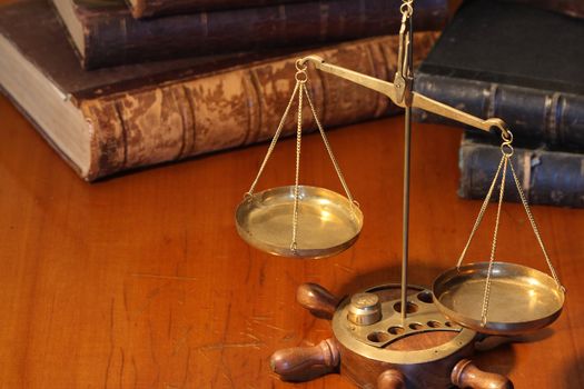 Ancient weight scale standing on wooden table near old books