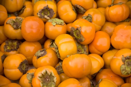 Ripe persimmons tiled on a market stall.