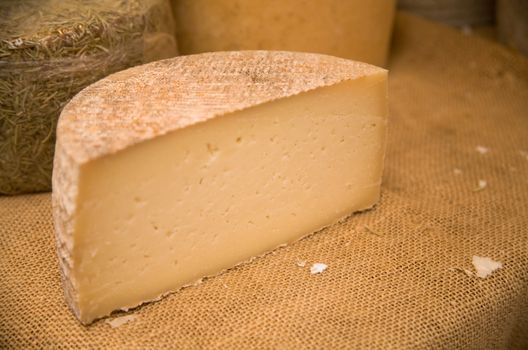 Cheeses on a market sacking covered stall. Shallow focus.