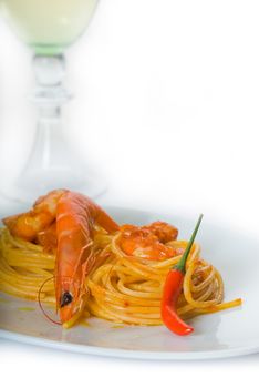 italian spaghetti pasta and fresh spicy shrimps sauce,with a grass of dry white wine on background