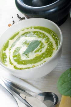 fresh spinach soup on a white bowl with sage and cream on top