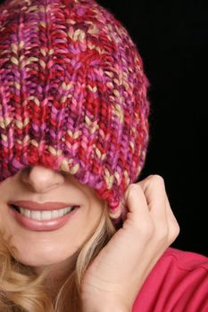 Girl pulls woollen beanie over face in playful manner