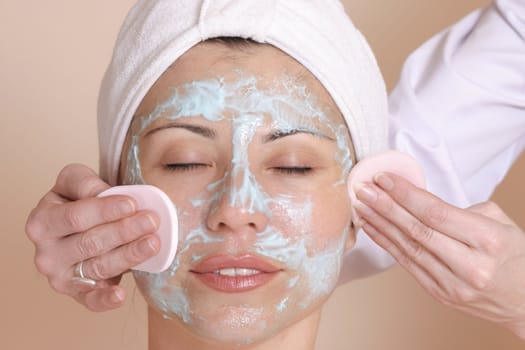 Beautician cleansing the skin of a female customer.