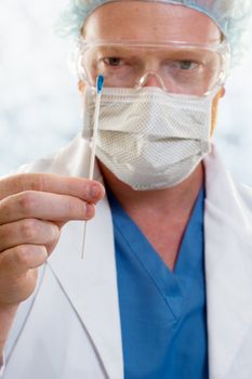 A man holding a swab.  Focus on hand and the swab.